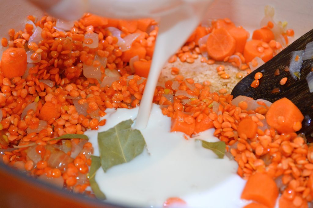 Adding coconut milk to Lentils, carrots, onions, and spices for Coconut Curry Lentil Soup