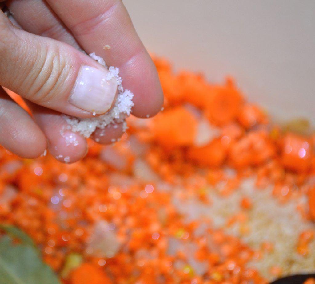 Adding salt to vegetables prepared for Coconut Curry Lentil Soup